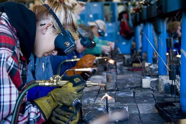 Female student welding wearing protective gear.