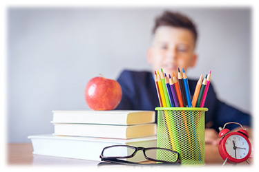 Image of student with apple, pencils, glasses, and clock